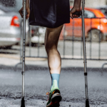 Male athlete with a disability without a leg on crutches running marathon.