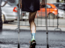 Male athlete with a disability without a leg on crutches running marathon.