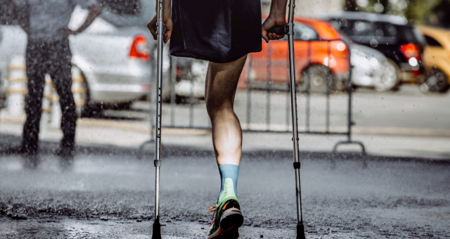 Male athlete with a disability without a leg on crutches running marathon.