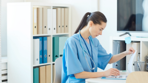 Female Medic Reading Documents in Clinic.