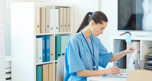 Female Medic Reading Documents in Clinic.