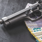 Hand gun and euro banknotes on black table.
